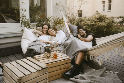 Portrait of smiling couple with female friend enjoying in backyard during social gathering