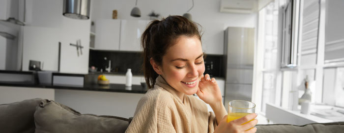 Side view of young woman drinking at home