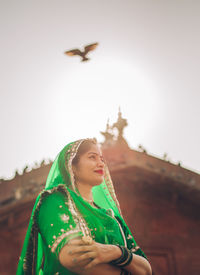 Portrait of smiling young woman flying against sky