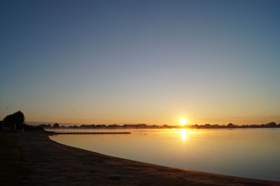 Scenic view of lake against clear sky during sunset