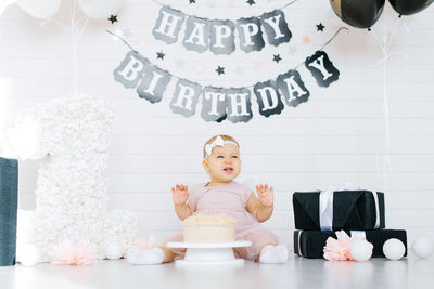 Celebrating the first birthday of a little girl. a child sits near a cake in a festive photo zone