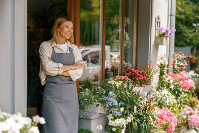 Portrait of smiling young woman standing in greenhouse