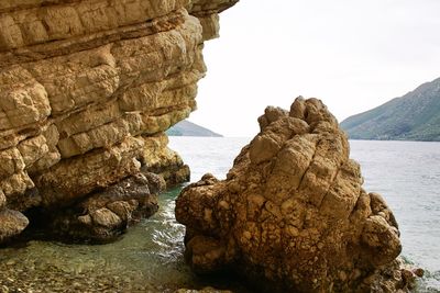 Rock formation on sea against clear sky