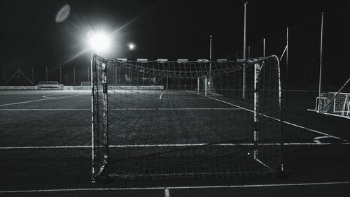 Illuminated lights on soccer field against sky at night