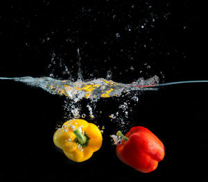 Close-up of bell peppers on water against black background