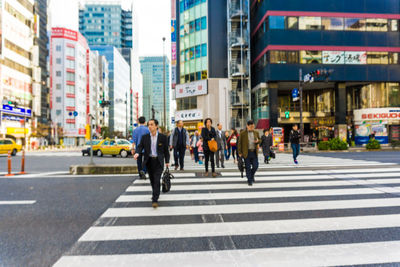 Group of people walking on road in city