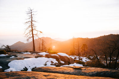 Snow covered landscape against sky during sunset