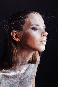 Close-up portrait of young woman against black background