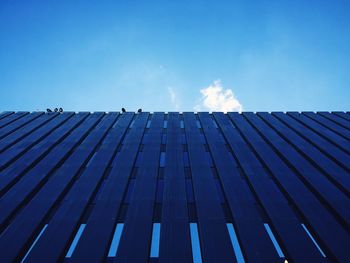 Low angle view of birds perching on modern building