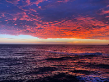 Scenic view of sea against dramatic sky during sunset