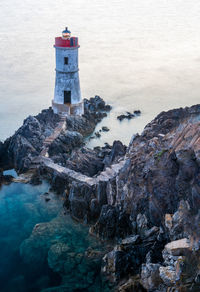 High angle view of lighthouse on rock formation by sea