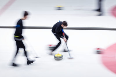 Blurred motion of people playing curling