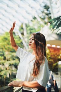 Young woman looking away while standing outdoors