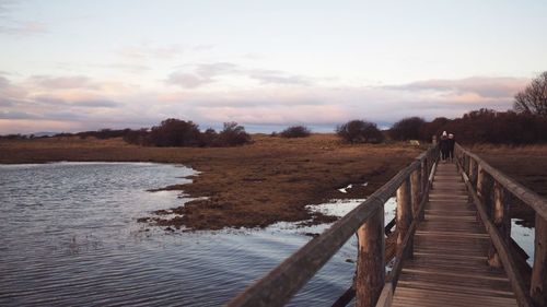 Pier over lake against sky during sunset