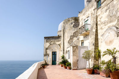 Exterior of building by sea against clear blue sky