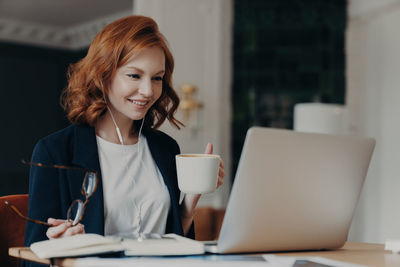 Young woman using mobile phone while sitting at table