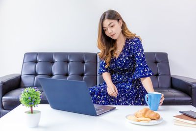 Young woman using phone while sitting on sofa