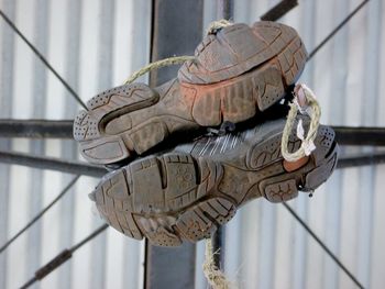 Close-up of shoes on railing against wall