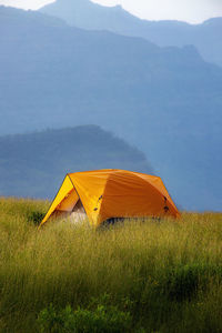 Tent on field by mountain against sky