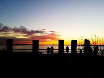 Silhouette people standing on beach against sky during sunset