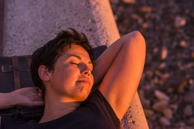 Woman sleeping on retaining wall in sunny day