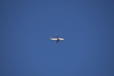 Low angle view of airplane against clear blue sky