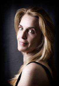 Portrait of smiling woman against black background