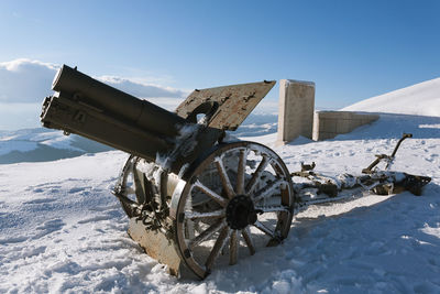 Bicycle on snow covered field against sky