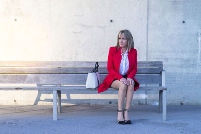Full length of mature woman sitting on bench outdoors