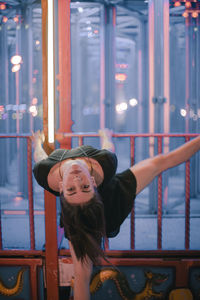 Portrait of smiling young woman standing against railing