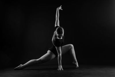 Low section of woman exercising against black background