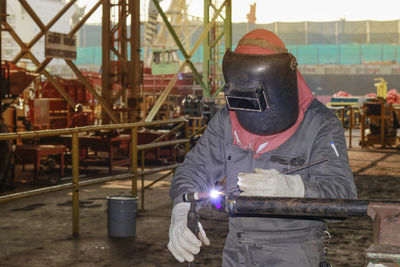 Man welding metal while standing in factory