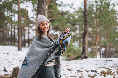 Young woman smiling in snow covered forest