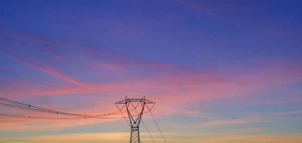 Low angle view of electricity pylon against romantic sky