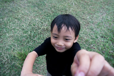 Side view of boy sitting on grassy field