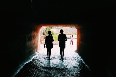 Rear view of people walking in tunnel