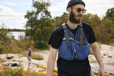 Man wearing life jacket standing on coast and looking away