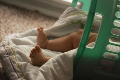 Low section of baby lying on bed