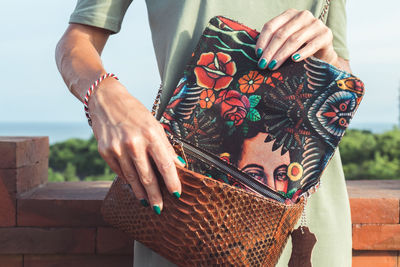 Girl on the background of tropical trees holding a bag made of python skin