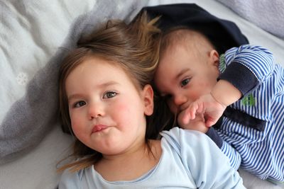 Portrait of cute siblings lying on bed