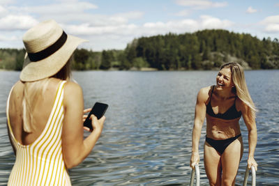 Woman photographing with mobile phone standing in water