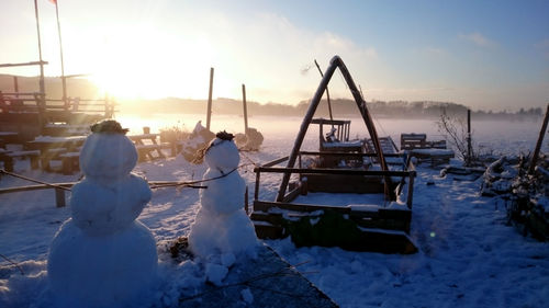 Sunrise on a winter field with snowman and gardening objects