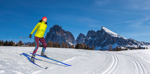 Woman skiing on snowcapped mountain against sky