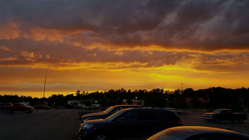 Cars on road against dramatic sky during sunset