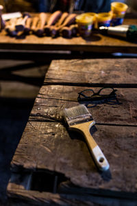 Close-up of paintbrush and eyeglasses on wooden table