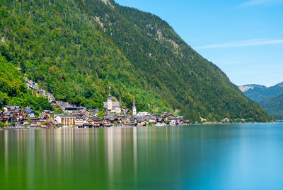 Buildings by sea against mountains and blue sky