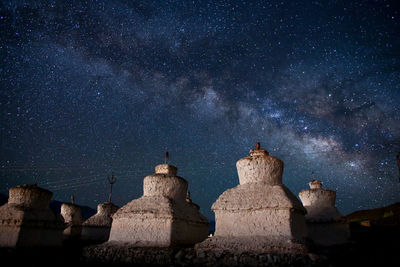 Low angle view of built structures against milky way at night