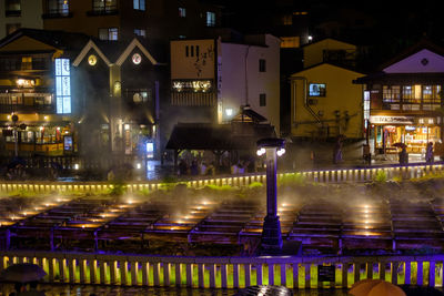 Illuminated buildings by street in city at night