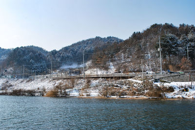 Bridge over river against clear sky during winter