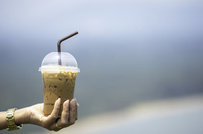 Midsection of person holding ice cream against sky